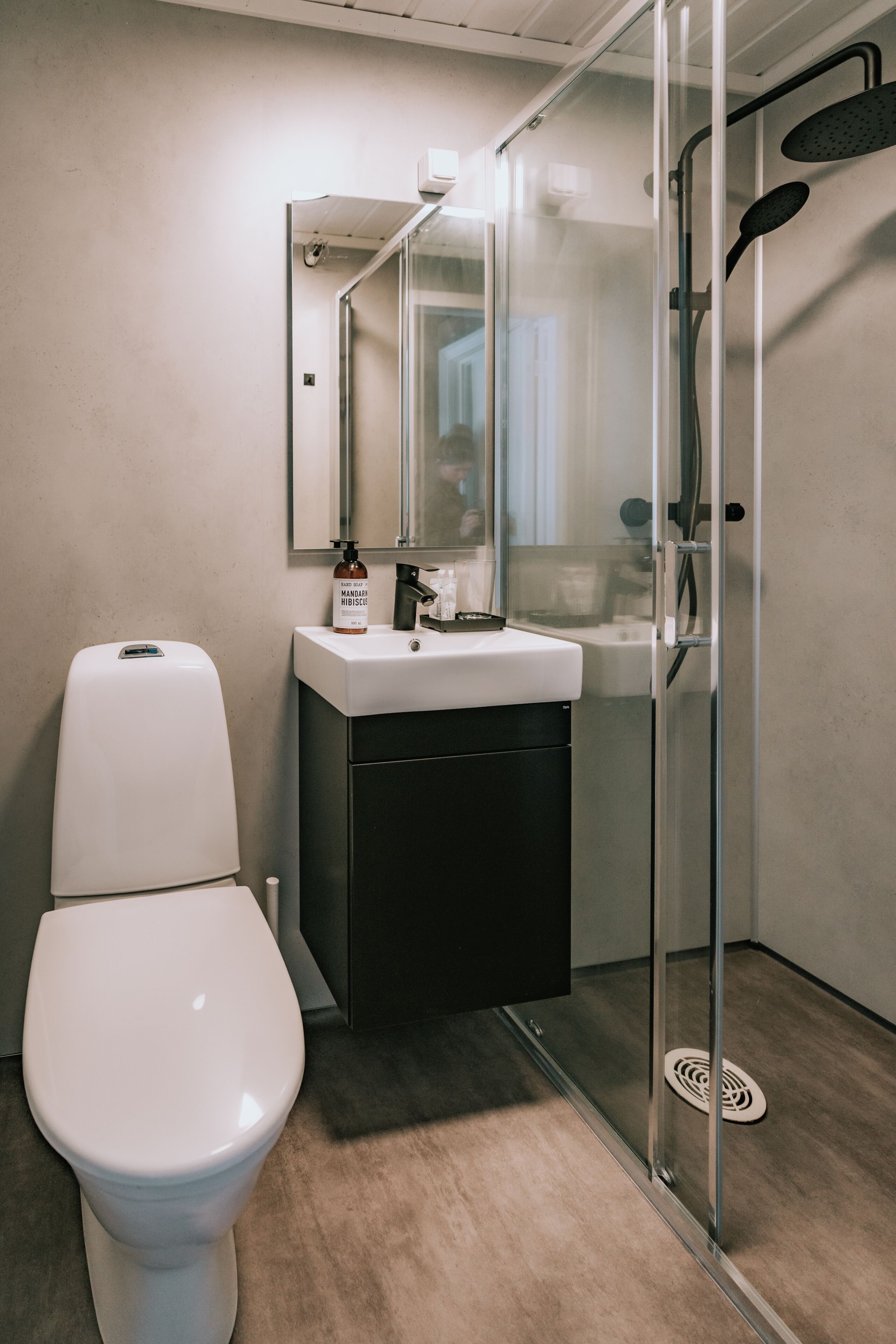 Un baño moderno con inodoro, lavamanos y cabina de ducha de vidrio.