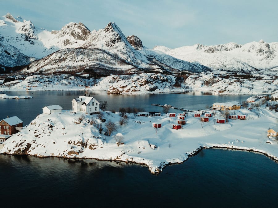 Un pueblo costero cubierto de nieve, con casas e iglesia junto al agua.