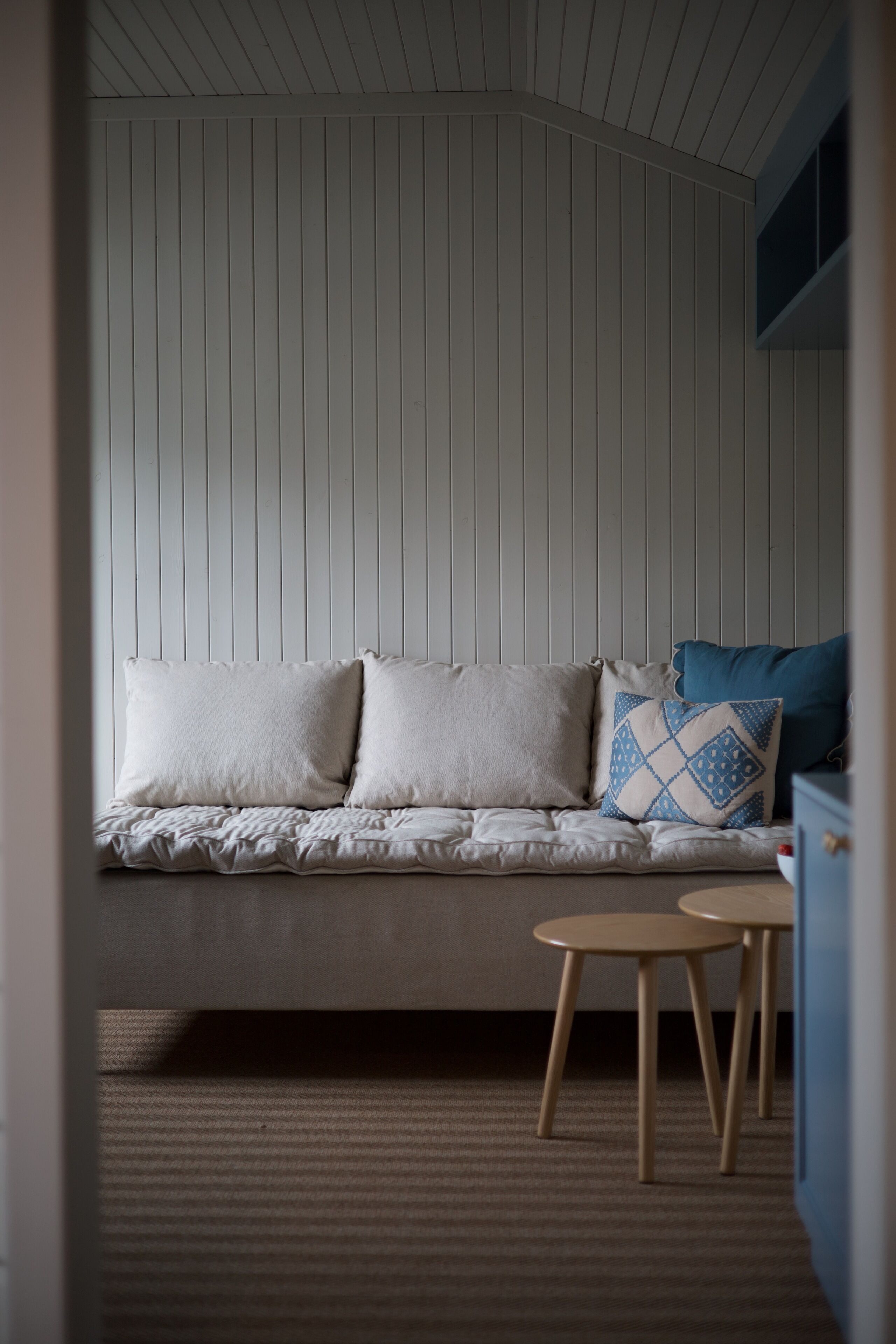 A room with a sofa, two small tables, and a blue cabinet.