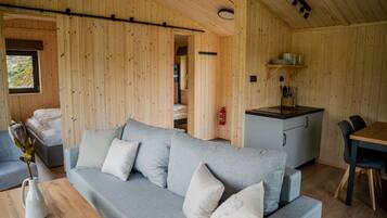 Un interior acogedor de madera, con un sofá gris, una mesa de comedor y una kitchenette.