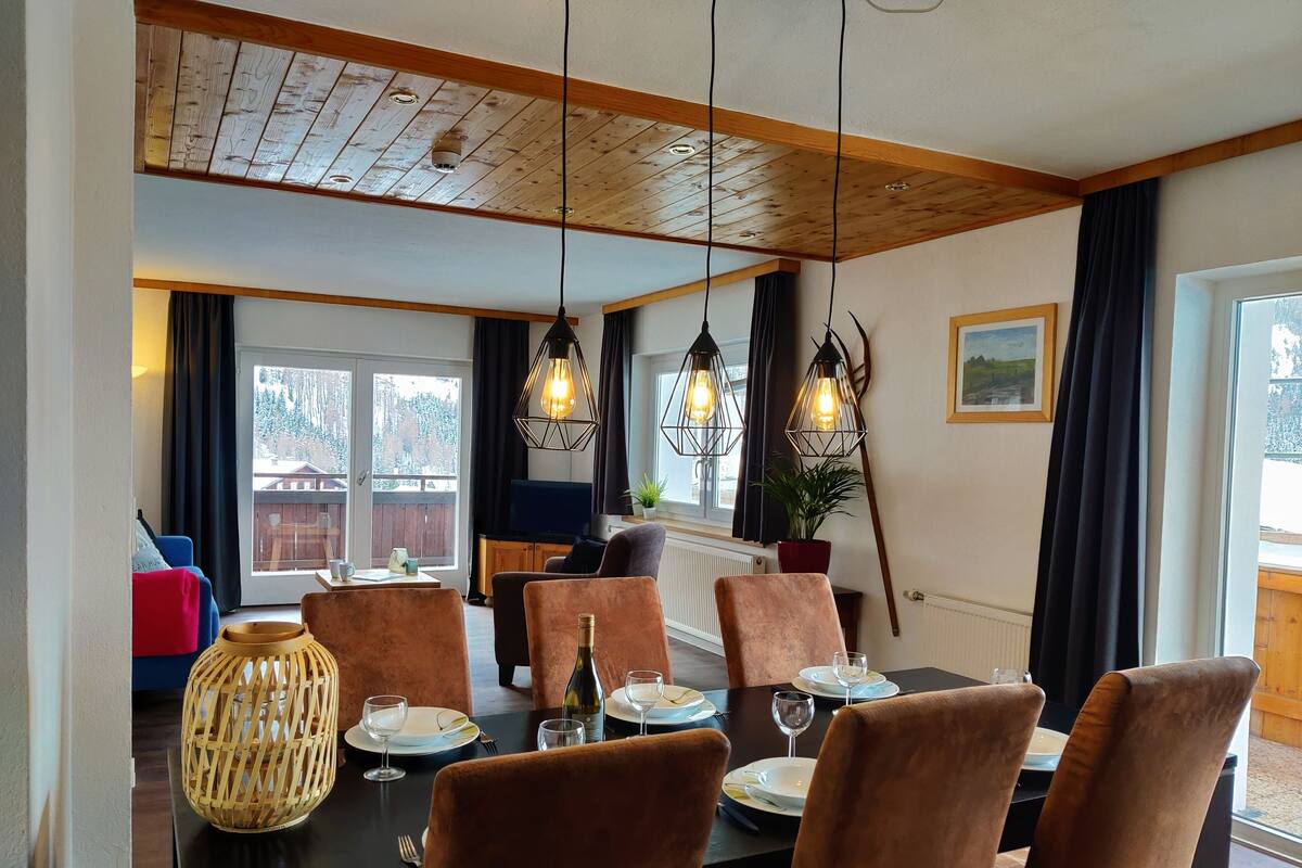 Ein Essbereich mit Holzboden, Pendelleuchten und einem Tisch für vier Personen mit Stühlen.