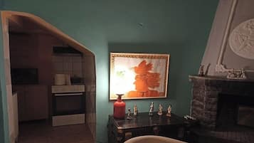 Cozy living room with a fireplace, comfortable armchair, and a kitchen area.