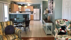 A compact living space with a dining area, kitchen, and seating area. - SANDY TAILS - Oak Island, NC (Oak Island)
