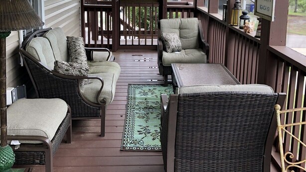 A covered porch with wicker furniture, a ceiling fan, and a view of a house in the background. - SANDY TAILS - Oak Island, NC (Oak Island)