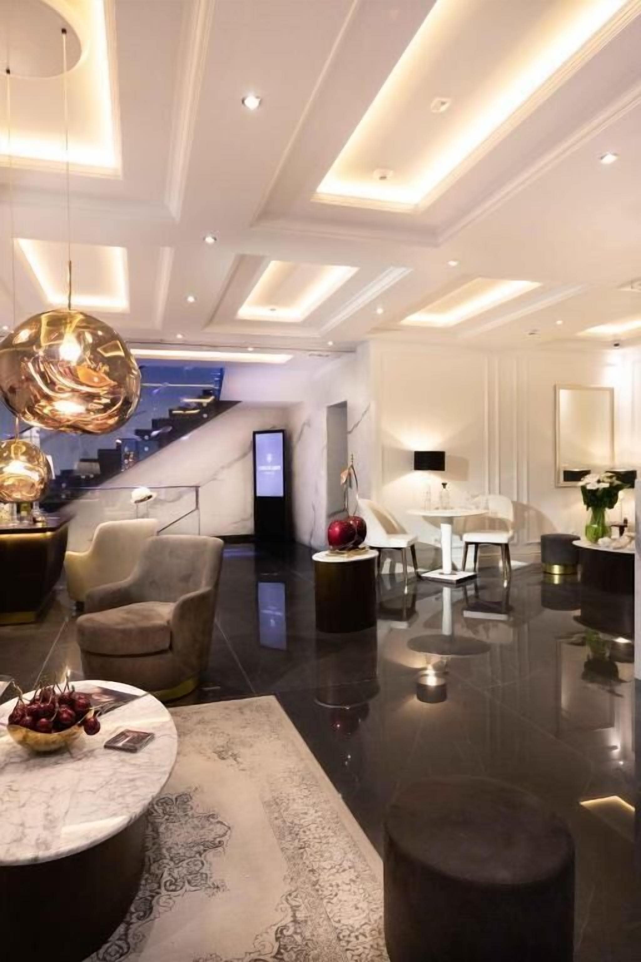 Un moderno vestíbulo de hotel con una recepción de mármol, asientos cómodos y una escalera que conduce a los pisos superiores.