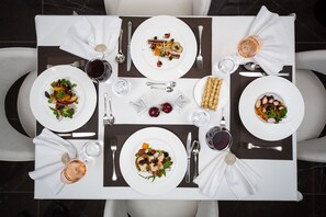 Ein gedeckter Tisch mit Speisen, Besteck und Gläsern mit Wasser und Wein.