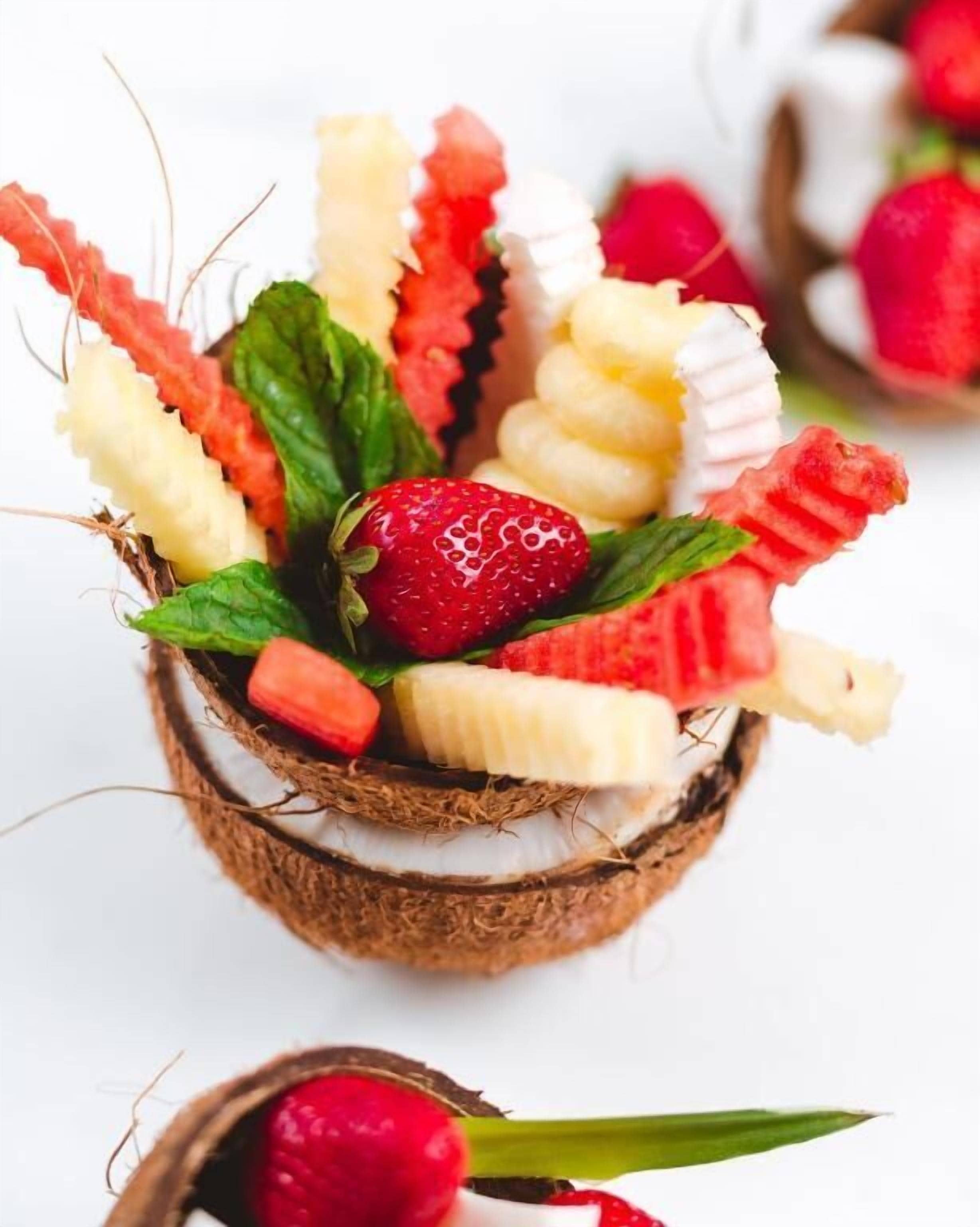 Una cesta con frutas variadas y un coco.