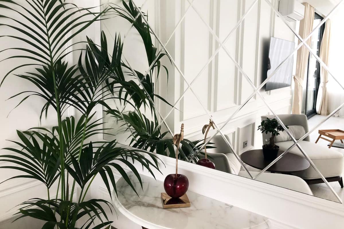 Un salon moderne avec une table basse en marbre, de grandes plantes vertes et un vase rouge décoratif.