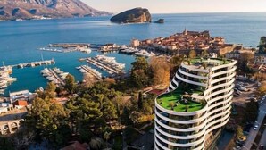 Un hôtel moderne à l’architecture originale, caractérisée par des lignes courbes, situé près d’une marina où sont amarrés des bateaux.