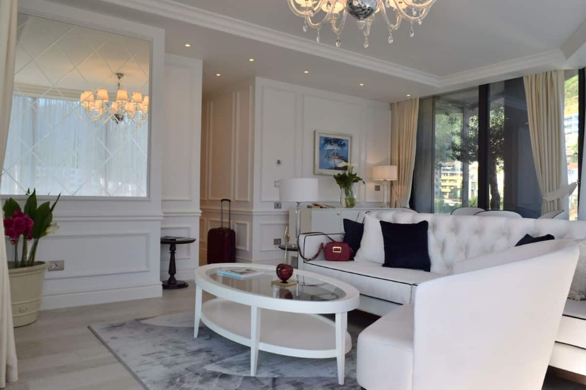 Un salon moderne avec un canapé blanc, une table basse en verre et un lustre.