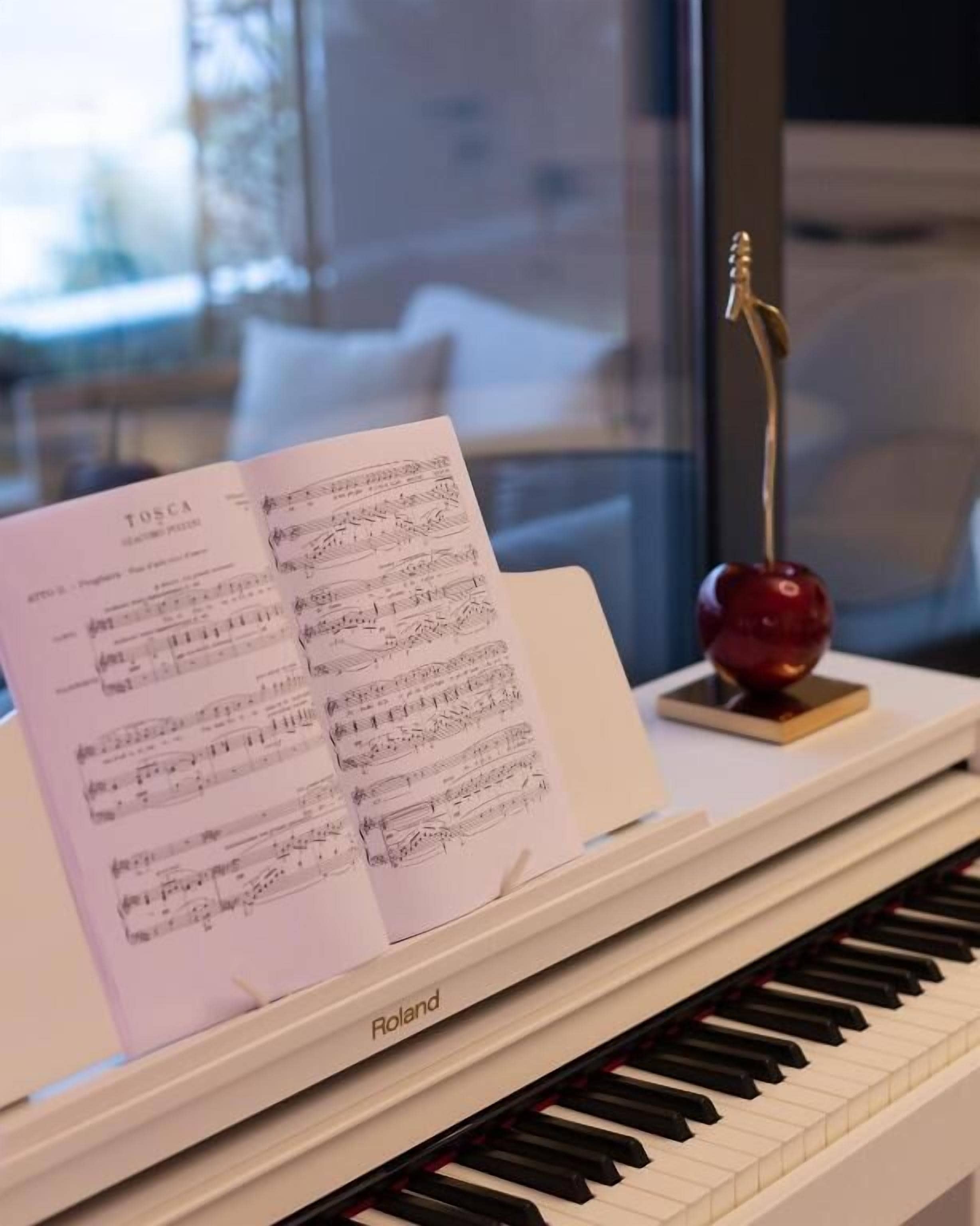 Un piano con partituras tituladas “Tosca” y un adorno encima.