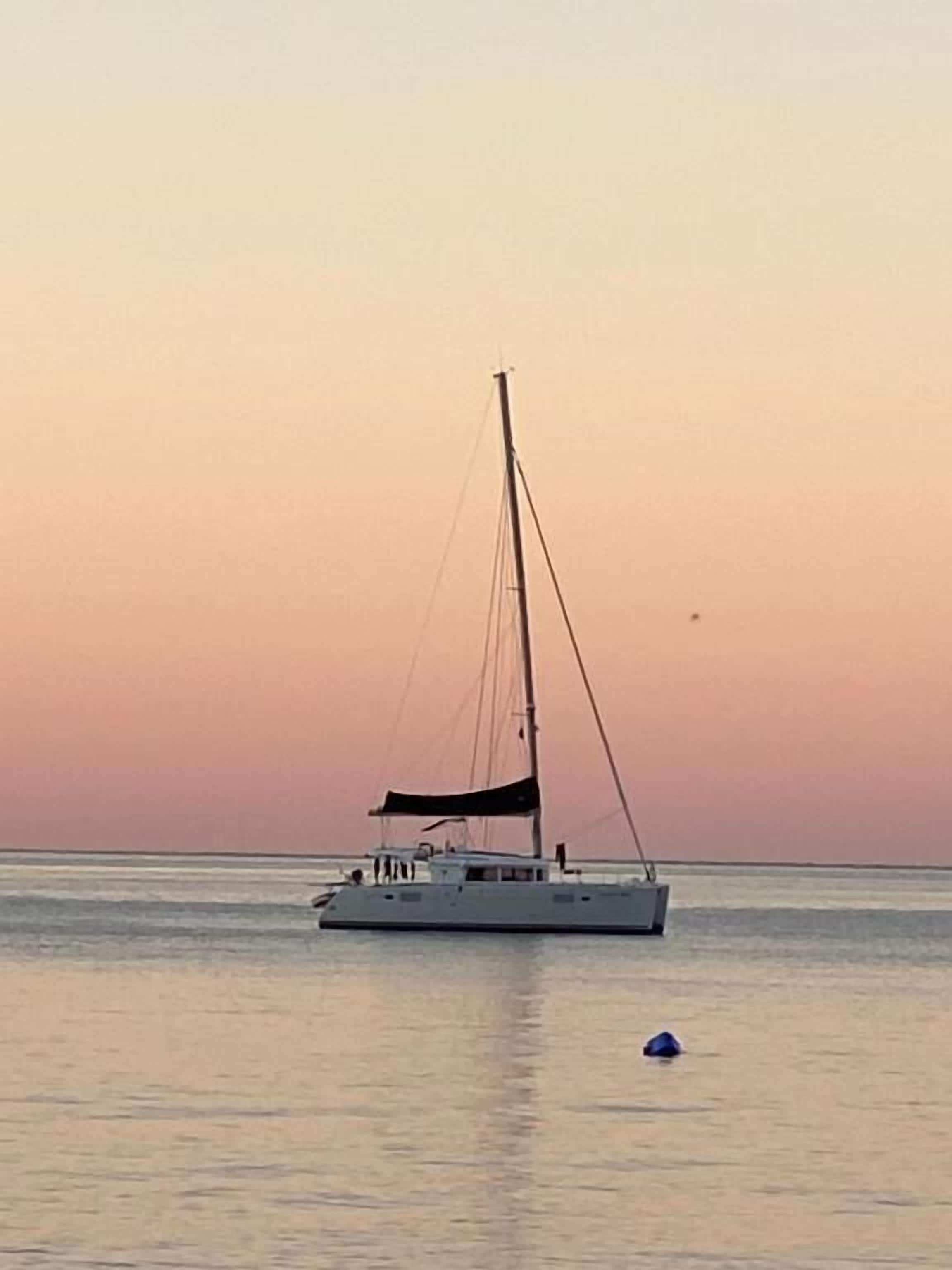 A sailboat on calm waters during sunset.
