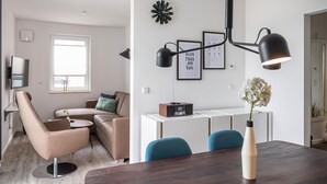 A modern living room with a sofa, a coffee table, and a dining area with a table and chairs. - Lovely apartment in Rechlin with lake view (Rechlin)