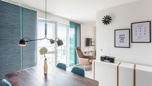 A modern dining area with a wooden table, blue chairs, a pendant light, and a TV on a stand. - Lovely apartment in Rechlin with lake view (Rechlin)