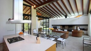 Una cocina amplia con una isla grande, comedor con sillas y una chimenea.