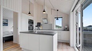 Une cuisine moderne avec des meubles blancs, un îlot central et des luminaires suspendus.