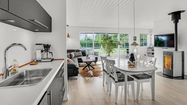 A modern kitchen with a coffee machine, a dining area with a table and chairs, and a fireplace. - Nice home in Kirke Hyllinge with WiFi (Kirke Hyllinge)