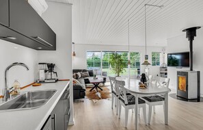 Eine moderne Küche mit Kaffeemaschine, ein Essbereich mit Tisch und Stühlen sowie ein Kamin.