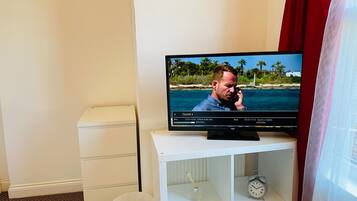 A television on a white stand displaying a man on a beach.