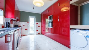 A modern kitchen with red cabinetry, a washing machine, and a large window. - Shirley House Self Catering Guest House, 5 min Drive to Cruise Ship Terminals and City Centre (Southampton)