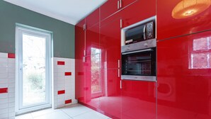 A modern kitchen with red cabinets, a double oven, and a large window. - Shirley House Self Catering Guest House, 5 min Drive to Cruise Ship Terminals and City Centre (Southampton)