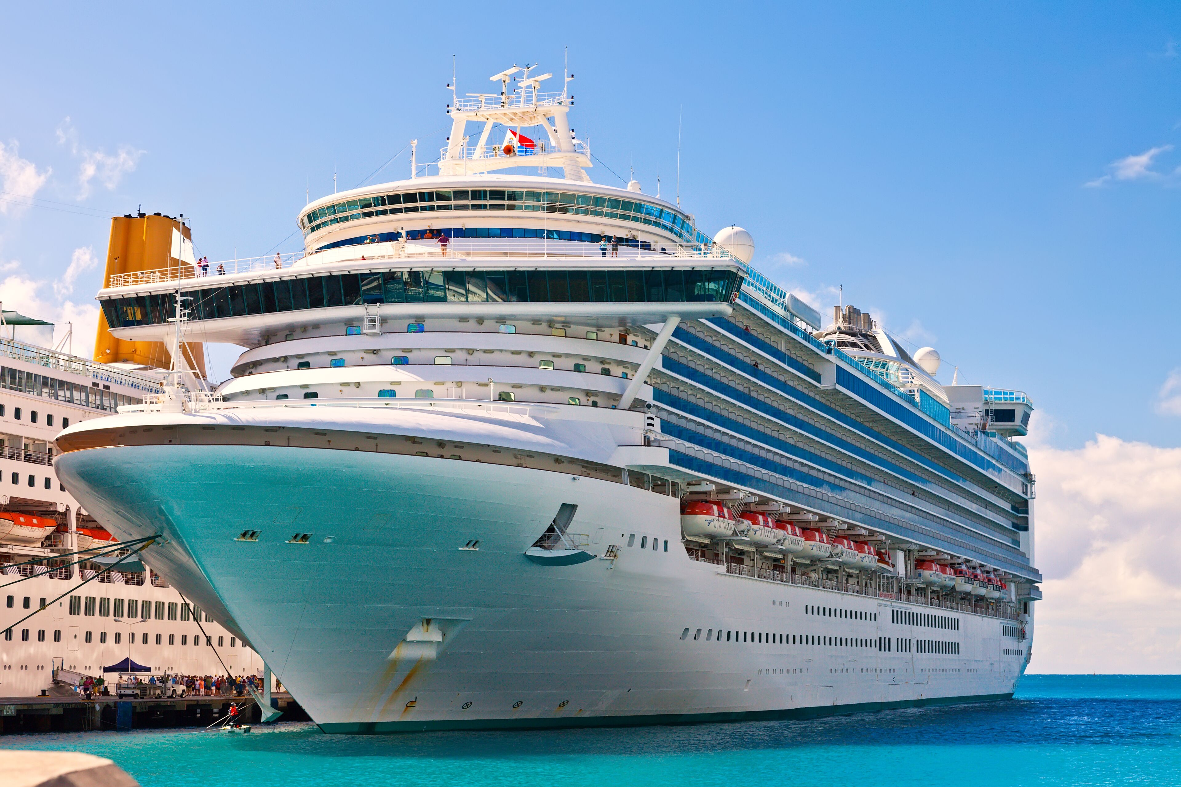 A large cruise ship docked at a port with multiple decks and balconies.