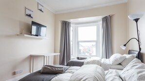 A bedroom with a bed, a desk, a TV, and a window with curtains. - Shirley House Self Catering Guest House, 5 min Drive to Cruise Ship Terminals and City Centre (Southampton)