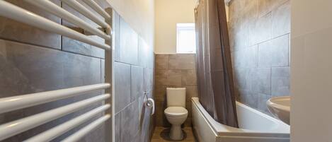A bathroom with a toilet, bathtub, and a towel rack.