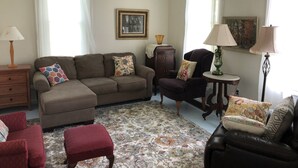 A living room with a brown sofa, red armchair, and a small table with a lamp. There is a patterned rug on the floor. - Have a Summer Holiday in Country Farmhouse (Schoolcraft)