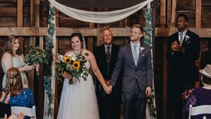 A wedding ceremony with a wooden backdrop, white chairs, and guests seated. - Have a Summer Holiday in Country Farmhouse (Schoolcraft)