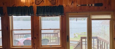 A cabin with wooden walls and a large window overlooking a lake.