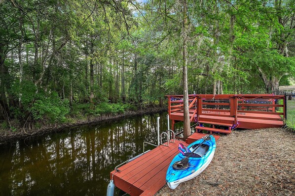 Une jetée en bois s’étendant dans une rivière paisible, entourée d’une forêt dense.