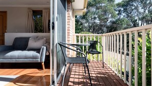 A balcony with a wooden floor, a sofa, and two chairs.