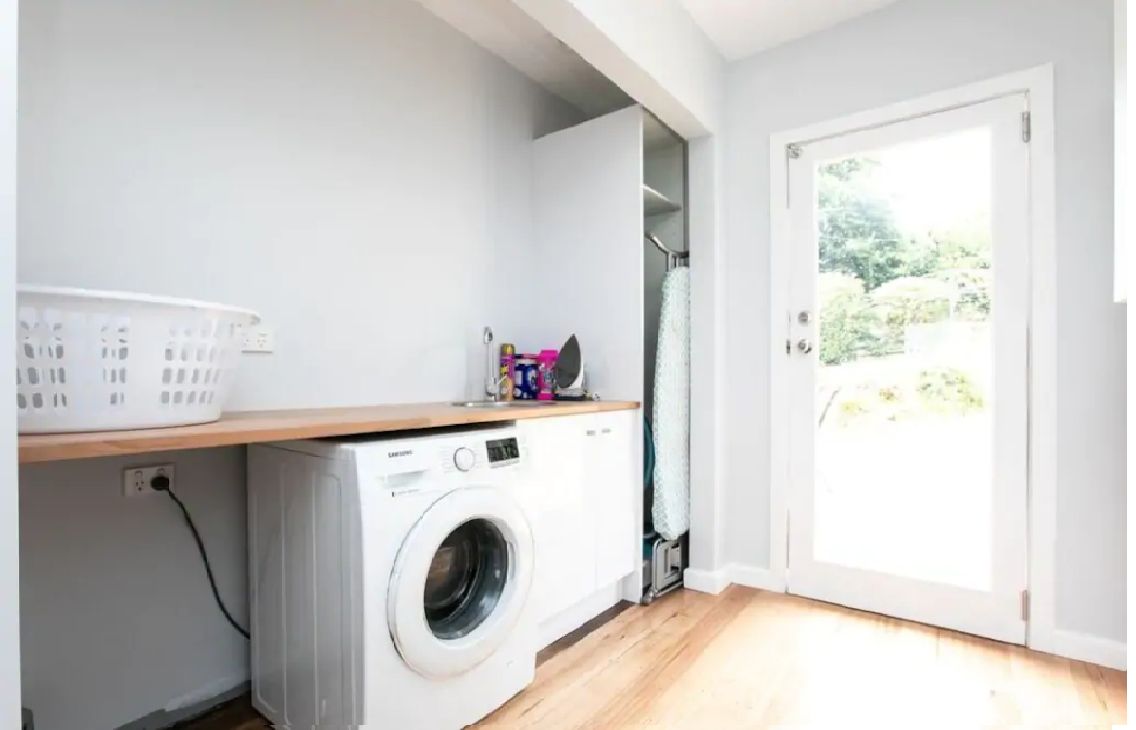 A laundry area with a washing machine, a drying rack, and a basket.