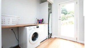 A laundry area with a washing machine, a drying rack, and a basket. - Family Escape | Views & Wi-Fi (Newstead)