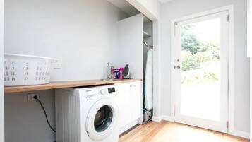 A laundry area with a washing machine, a drying rack, and a basket.