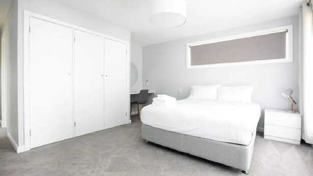 A modern bedroom with a large bed, a desk, and a wardrobe. - Family Escape | Views & Wi-Fi (Newstead)