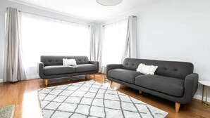 A modern living room with two dark sofas, a white rug, and a ceiling light. - Family Escape | Views & Wi-Fi (Newstead)
