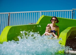 A person and a child at the bottom of a water slide. - 4 Bedroom Lakeview home next to Margaritaville (Osage Beach)