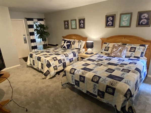 A bedroom with two beds, a nightstand, a lamp, and a door leading to another room. - 4 Bedroom Lakeview home next to Margaritaville (Osage Beach)