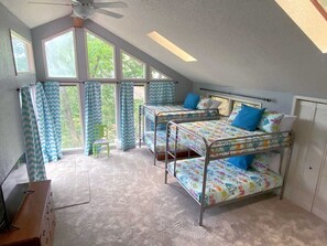 Ein Schlafsaalzimmer mit Etagenbetten, einem Schreibtisch und einem Fenster mit Vorhängen.