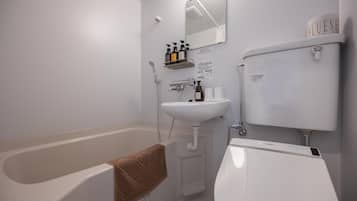 A bathroom with a bathtub, a sink, and a toilet. There are toiletries on a shelf above the sink.