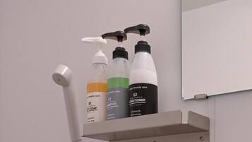 A bathroom shelf with three bottles of personal care products and a soap dispenser.
