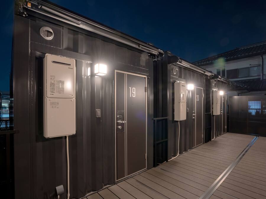 A row of metal cabins with doors numbered 19 and 20, each with a small window and a light fixture above the door.