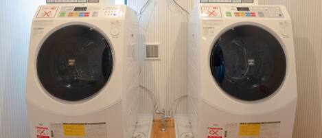 Two identical front-loading washing machines with control panels, placed side by side on a wooden floor.