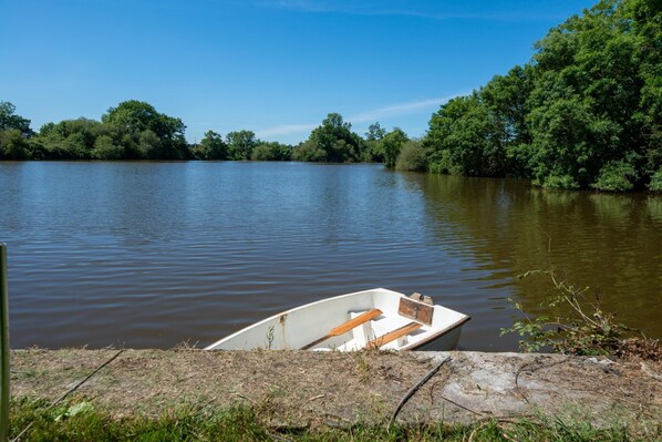A small boat docked at a calm river with dense trees in the background.