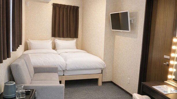 Una habitación de hotel con cama, sofá, escritorio con espejo y televisión.