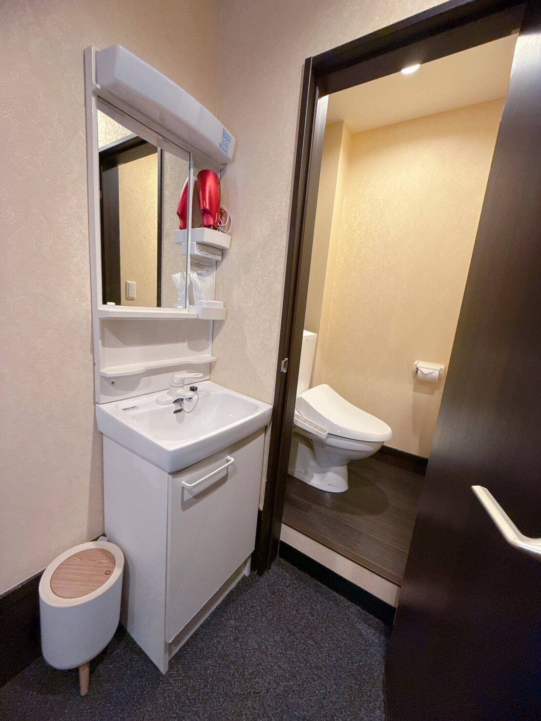 A modern bathroom with a white sink, mirror, and toilet.