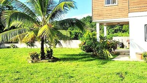 Ein zweistöckiges Haus mit gepflegtem Rasen und einer Palme.
