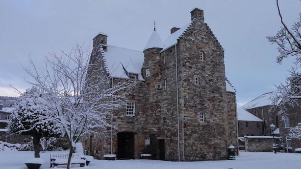 Un edificio de piedra con una torre y un patio cubierto de nieve.